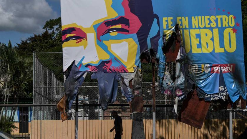 A man walks under a giant billboard with the image of Venezuelan President Nicolas Maduro, which was vandalized during strong protests against the results of Venezuela's presidential election in Valencia, Carabobo State, Venezuela, on July 31, 2024. Yuri CORTEZ / AFP